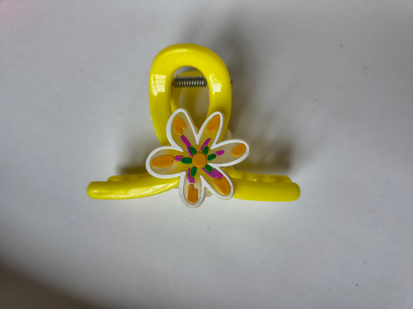 Stylish yellow claw clip with colorful floral charm.